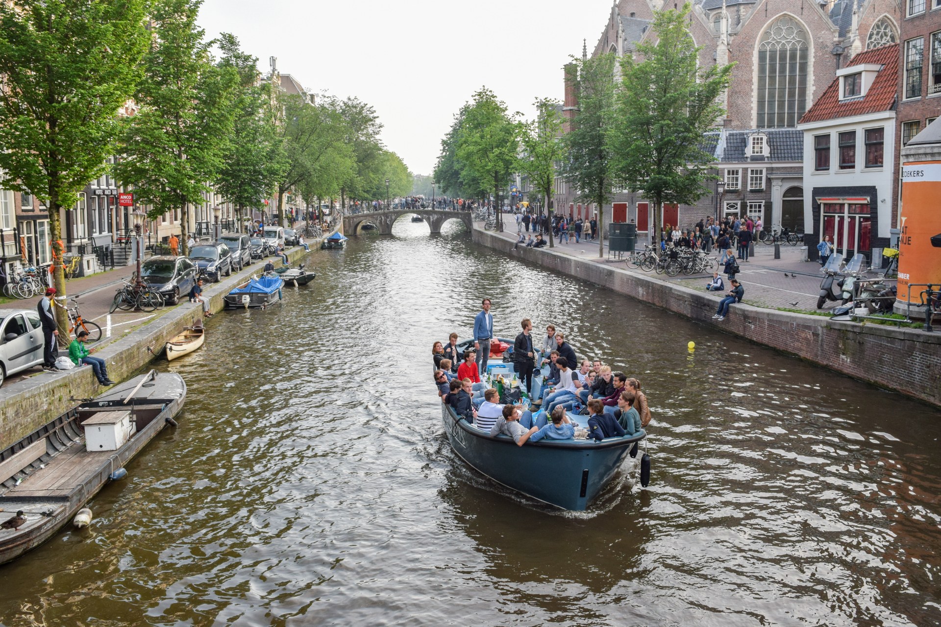 Młodzi ludzie płyną łodzią po kanale w Amsterdamie